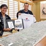 宇谷の立体地図を前に「集落の教科書」やＴシャツを手にする三崎雄太さん（左）と堂原克太さん＝洲本市五色町鮎原宇谷