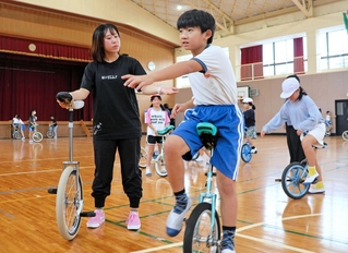 堀田綾菜さん（左端）の手ほどきで一輪車を練習する湊小学校の児童＝南あわじ市湊里