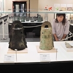 和歌山県で出土した銅鐸（手前）と松帆銅鐸（後ろ）が並ぶ特別展＝南あわじ市松帆西路