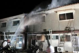 集合住宅に放水する消防署員ら＝２４日午前４時１分、姫路市