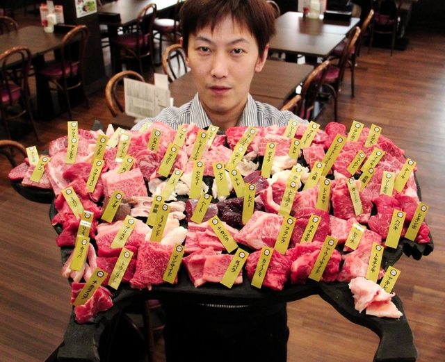 但馬牛を１頭丸ごとさばいた６１部位を食べ比べできるバーベキューメニューをＰＲする石原亮さん＝道の駅「村岡ファームガーデン」