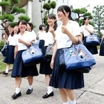 「ＫＯＮＡＮ」の刺しゅうが入ったファミリアのオリジナルかばんを持って歩く甲南女子高校の生徒たち＝神戸市東灘区森北町