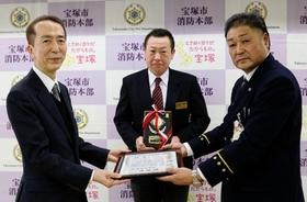 石橋豊消防長から感謝状を受け取る宝塚大劇場の小澤正道さん（中央）と野村洋一郎さん（左）＝宝塚市消防本部