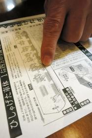 事故当時の新聞記事のコピーを指さし、車内の様子を説明する野田純嗣さん＝神戸市中央区