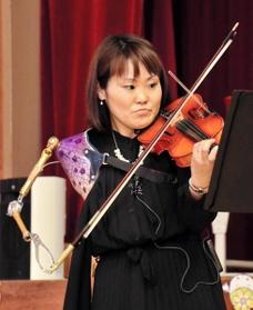 全身を使い、義手でバイオリンを弾く伊藤真波さん＝三木市立豊地小学校