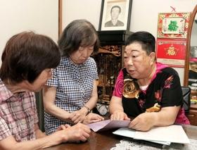 戸籍謄本を見ながら、日本語支援ボランティアらにルーツを語る前田麗子さん（右）。共に苦労した夫馬棟さんの遺影に見守られながら暮らす＝明石市魚住町清水