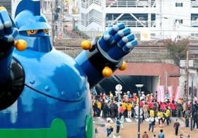 震災復興の象徴でもある鉄人２８号のモニュメント脇を通るコース。沿道の応援を受けてランナーが走る＝神戸市長田区若松町６