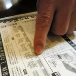 事故当時の新聞記事のコピーを指さし、車内の様子を説明する野田純嗣さん＝神戸市中央区