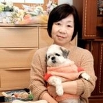 宏一さんの写真の前で、愛犬の夢ちゃんを抱く小前恵さん＝三田市
