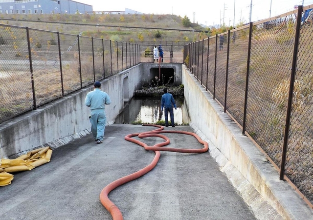 王子池（左フェンス奥）の手前にある沈砂池から水や土砂を回収する作業員ら＝１６日、三田市テクノパーク（市提供）