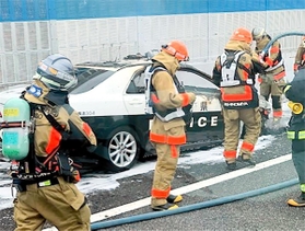消防隊員によって火が消し止められた兵庫県警のパトカー＝２７日午前１１時６分、西宮市今津久寿川町の阪神高速神戸線（読者提供）