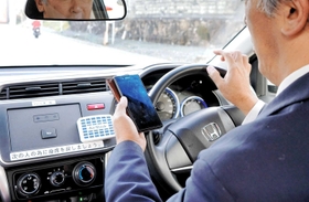 「ながら運転」の危険性を周知するイベントは各地で開かれている。ハンドルを握りながらスマートフォンを操作し、危険性を認識する参加者＝２０１９年１１月２８日丹波篠山市内