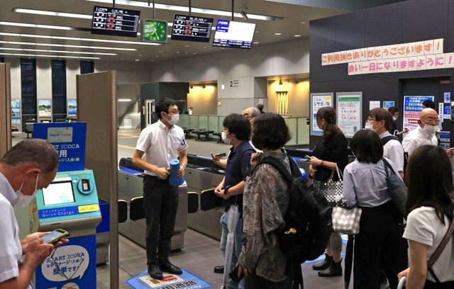 人身事故の影響で運転が見合わせになり、駅員に振り替え輸送の状況などを尋ねる人たち＝１９日午後７時２６分、神戸市灘区、ＪＲ灘駅