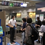 人身事故の影響で運転が見合わせになり、駅員に振り替え輸送の状況などを尋ねる人たち＝１９日午後７時２６分、神戸市灘区、ＪＲ灘駅