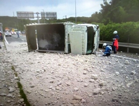 トラックが横転し、荷台からこぼれ出たコンクリート片が道路をふさいだ＝１２日午前、神戸市西区伊川谷町（兵庫県警提供）