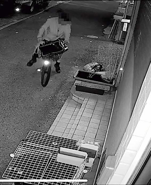 自転車にまたがったまま、メダカの水槽をのぞき込もうとする男（画像の一部を加工しています）