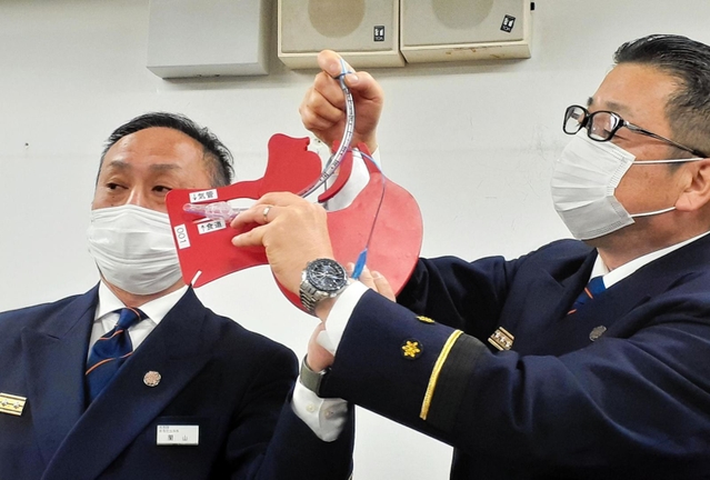 気道確保用チューブの挿管方法を説明する尼崎市消防局の渡辺賢一救急課長（右）ら。あおむけの状態で上側の気管に入れるところを、下側の食道に入れてしまっていた＝尼崎市役所