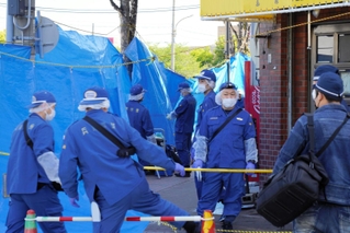 ラーメン店の店主が殺害された事件で、立ち入りを規制して現場の周辺を調べる捜査員ら＝２３日午前、神戸市長田区東尻池町９