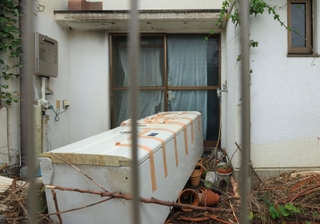 亡くなった男児らが住んでいた住宅の庭。冷蔵庫が放置され、窓にはテープが貼られていた＝２３日午前、神戸市西区玉津町居住