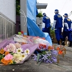 容疑者の自宅へと向かう兵庫県警の捜査員。集合住宅の一角に、花束や菓子が供えられていた＝２４日午後、神戸市西区玉津町居住