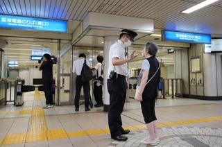 車両故障による運転見合わせを乗客に説明する阪神電鉄の社員＝２４日午後９時２１分、阪神春日野道駅