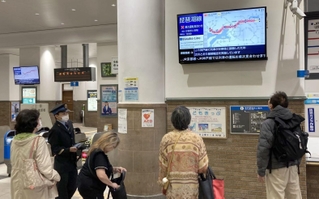 運転見合わせとなり、電光掲示板を見つめる利用客ら＝８日午前９時３２分、ＪＲ神戸駅