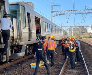 緊急停車した車両のそばで、事故対応に追われるＪＲ西日本の職員ら＝８日午前９時３６分、ＪＲ元町駅付近