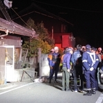 爆発で窓やドアが壊れた民家の前で原因を調べる消防隊員や警察官たち＝12日午後10時３分、丹波市山南町長野