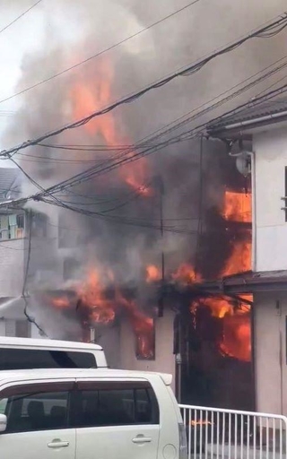 窓から炎を上げて燃える長屋＝２０日午後、尼崎市瓦宮１（読者提供）