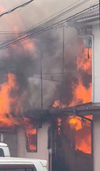 窓から炎と煙を上げて燃える長屋＝２０日午後、兵庫県尼崎市瓦宮１（読者提供）