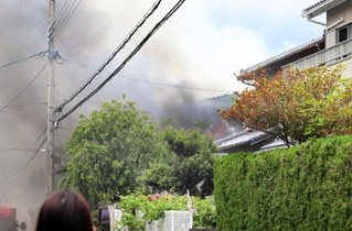 煙を上げて燃える民家＝８日午前１１時１６分、川西市向陽台２