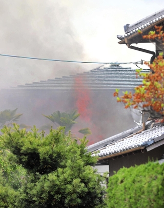 煙を上げて燃える民家＝８日午前１１時１５分、川西市向陽台２
