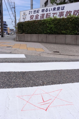 西宮署前の横断歩道上に書かれた六芒星と郵便マークを組み合わせたような記号＝西宮市津田町