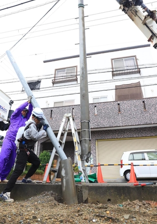 電柱が折れ、応急処置をする作業員ら＝１８日午前１０時３分、伊丹市東野２