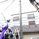 電柱が折れ、応急処置をする作業員ら＝１８日午前１０時３分、伊丹市東野２