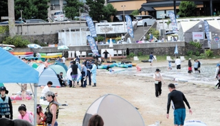 男性が海面で浮いているのが見つかった竹野浜海水浴場で、関係者から事情を聴く兵庫県警豊岡署員ら＝同県豊岡市竹野町竹野