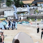 男性が海面で浮いているのが見つかった竹野浜海水浴場で、関係者から事情を聴く兵庫県警豊岡署員ら＝同県豊岡市竹野町竹野