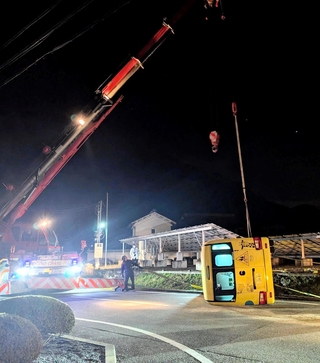 横転し、クレーンで引き上げられる送迎バス＝20日夜、丹波市山南町谷川
