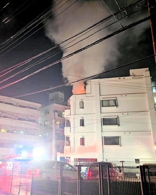 上層階から出火し、煙を上げるマンション＝２７日夜、神戸市垂水区清水が丘３