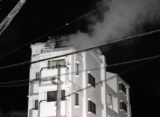 煙を上げるマンション＝27日午後10時47分、神戸市垂水区清水が丘３