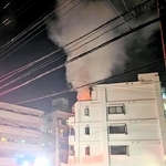 上層階から出火し、煙を上げるマンション＝２７日夜、神戸市垂水区清水が丘３