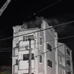煙を上げるマンション＝27日午後10時56分、神戸市垂水区清水が丘３