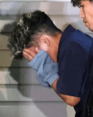 捜査員に付き添われ、葺合署に入る谷本将志容疑者＝２２日午後１１時４２分、神戸市中央区吾妻通５