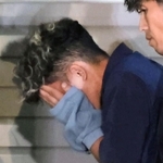 捜査員に付き添われ、葺合署に入る谷本将志容疑者＝２２日午後１１時４２分、神戸市中央区吾妻通５
