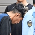 捜査員に連れられて警察車両に乗り込む谷本将志容疑者＝２４日午前９時２３分、神戸市中央区吾妻通５