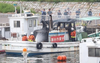 火災で一部が焼けた船で消火活動をする消防隊員ら＝神戸市灘区灘浜町
