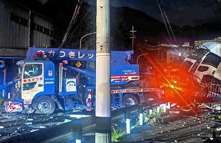信号柱などに衝突する事故を起こしたレッカー車。周辺にはけん引していたトラックの積み荷が散乱した＝２０日夜、神戸市灘区（読者提供）