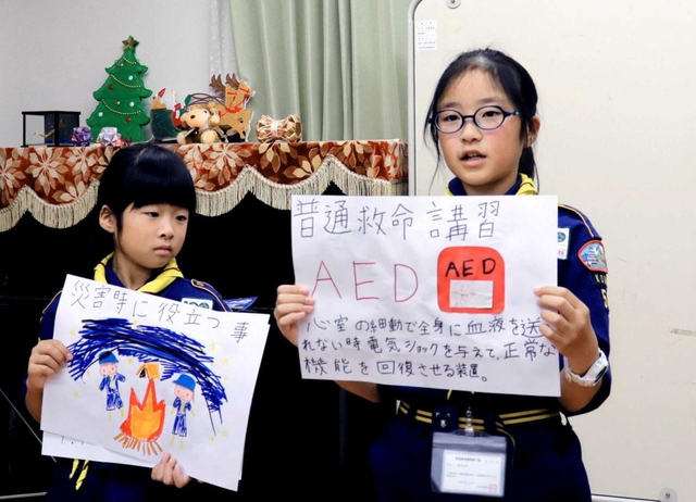 ボーイスカウトの仲間たちに防災の大切さを説明する防災士の酒井牡丹さん（右）＝神戸市東灘区