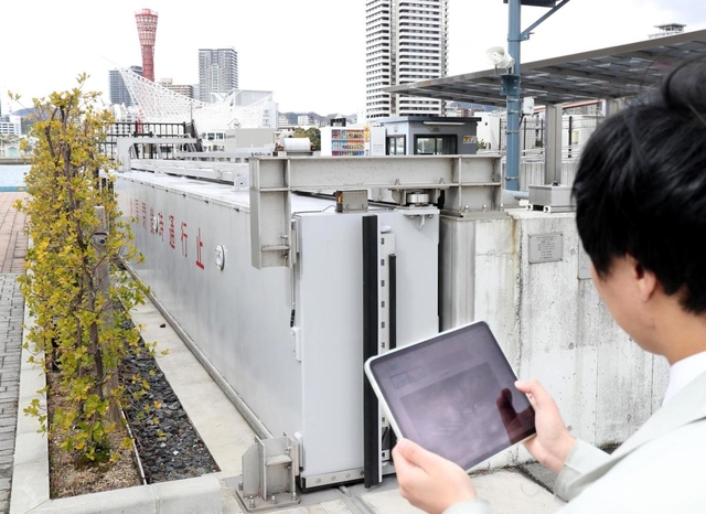 タブレットを使い、防潮扉を遠隔操作で開閉する市職員。実際は庁舎や自宅などで操作する＝神戸市中央区新港町（撮影・辰巳直之）