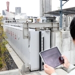 タブレットを使い、防潮扉を遠隔操作で開閉する市職員。実際は庁舎や自宅などで操作する＝神戸市中央区新港町（撮影・辰巳直之）